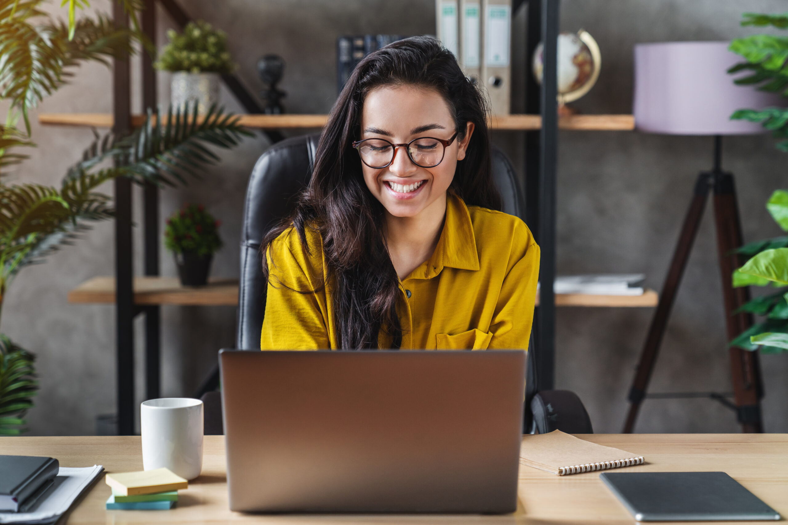 Young happy cute business woman sit indoors in home office using laptop computer
